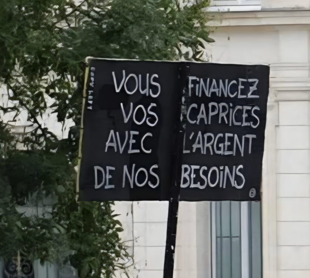Pancarte avec le slogan : "Vous financez vos caprices avec l'argent de nos besoins"